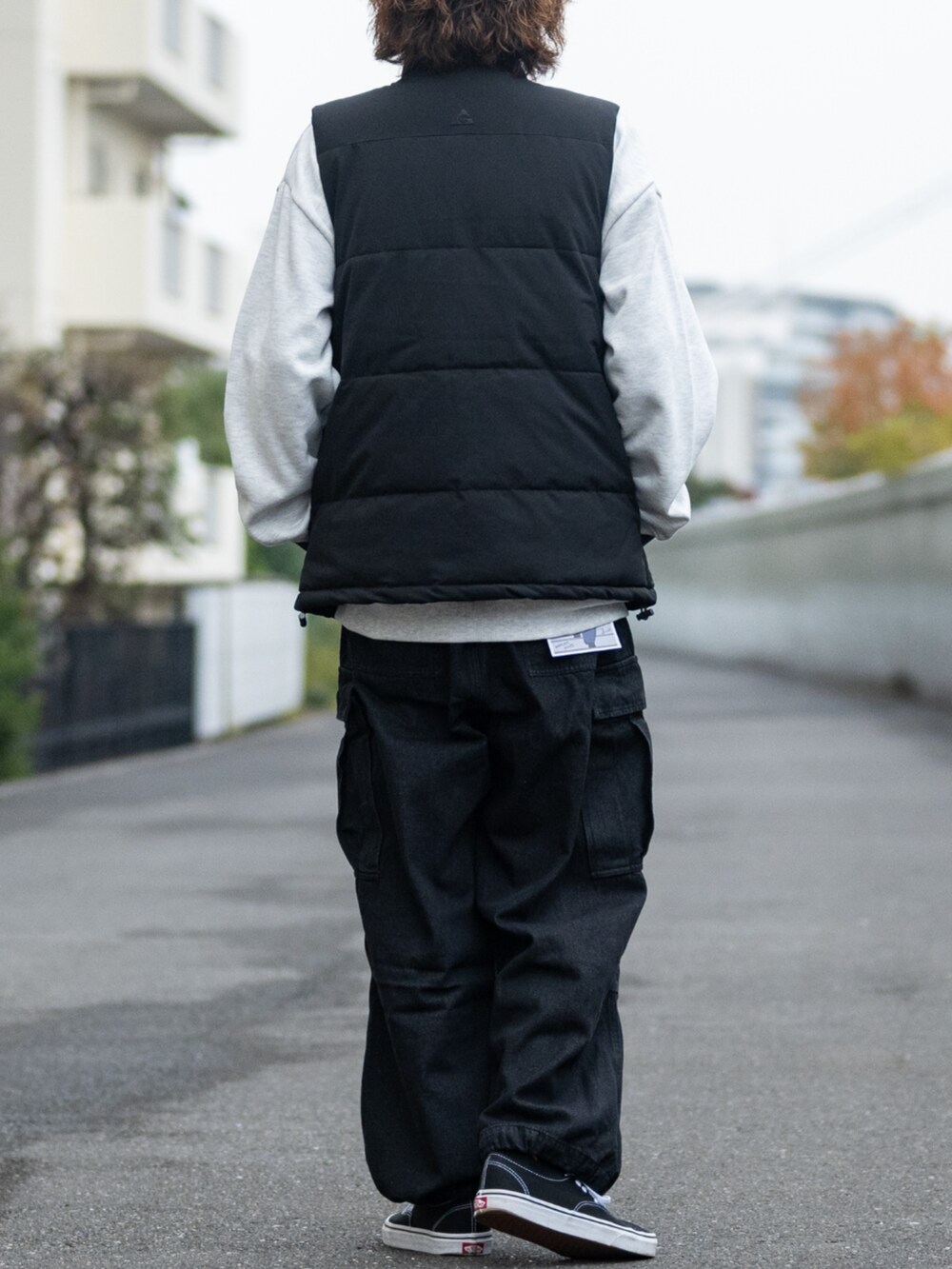 ブラック系のデニムパンツ、ベージュ系のスウェット、ブラック系のダウンベストを着用したメンズの冬コーディネートの3枚目の写真