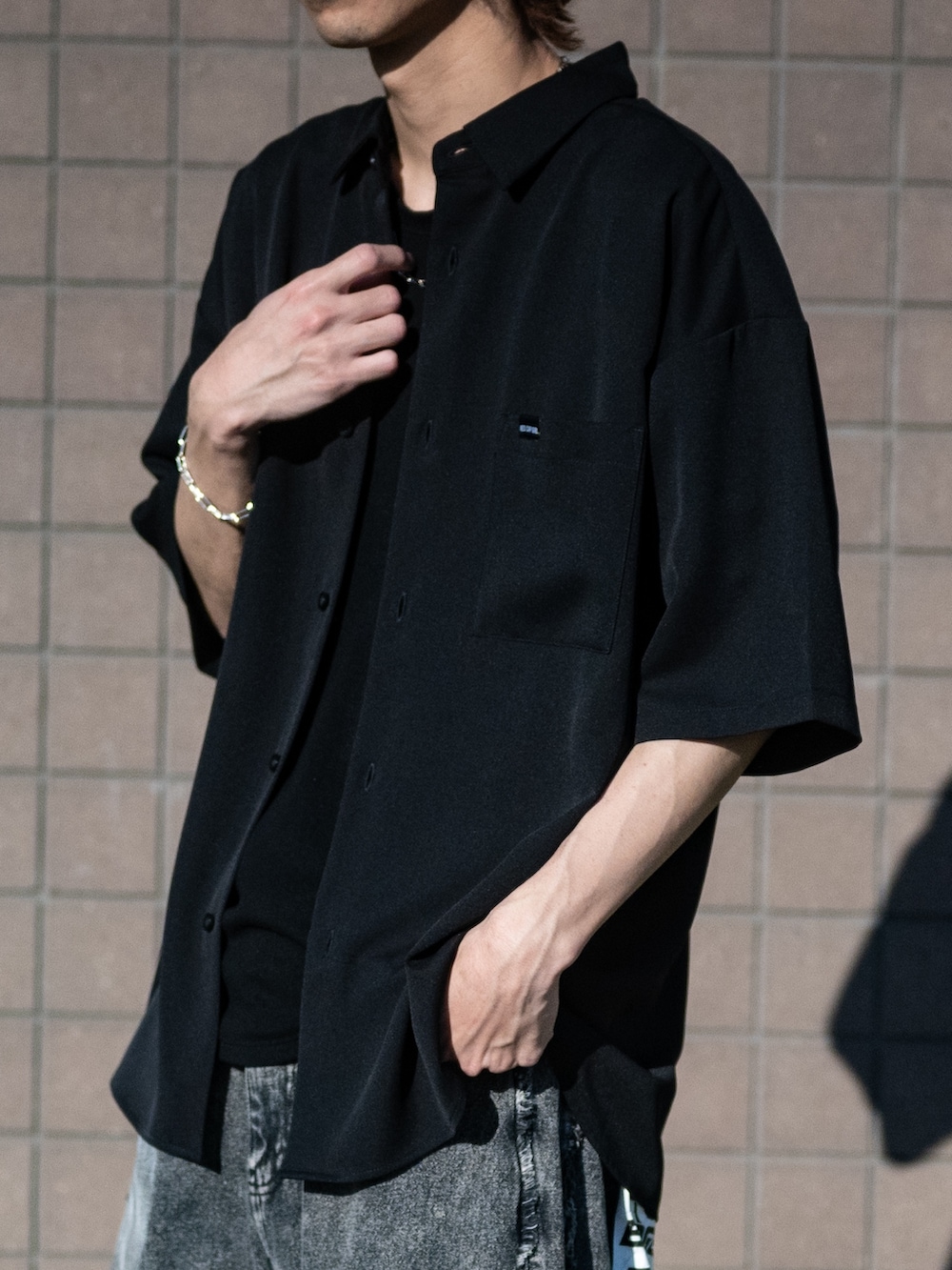 ブラック系のデニムパンツ、ホワイト系のスニーカー、ブラック系のシャツ/ブラウスを着用したメンズの春コーディネートの5枚目の写真