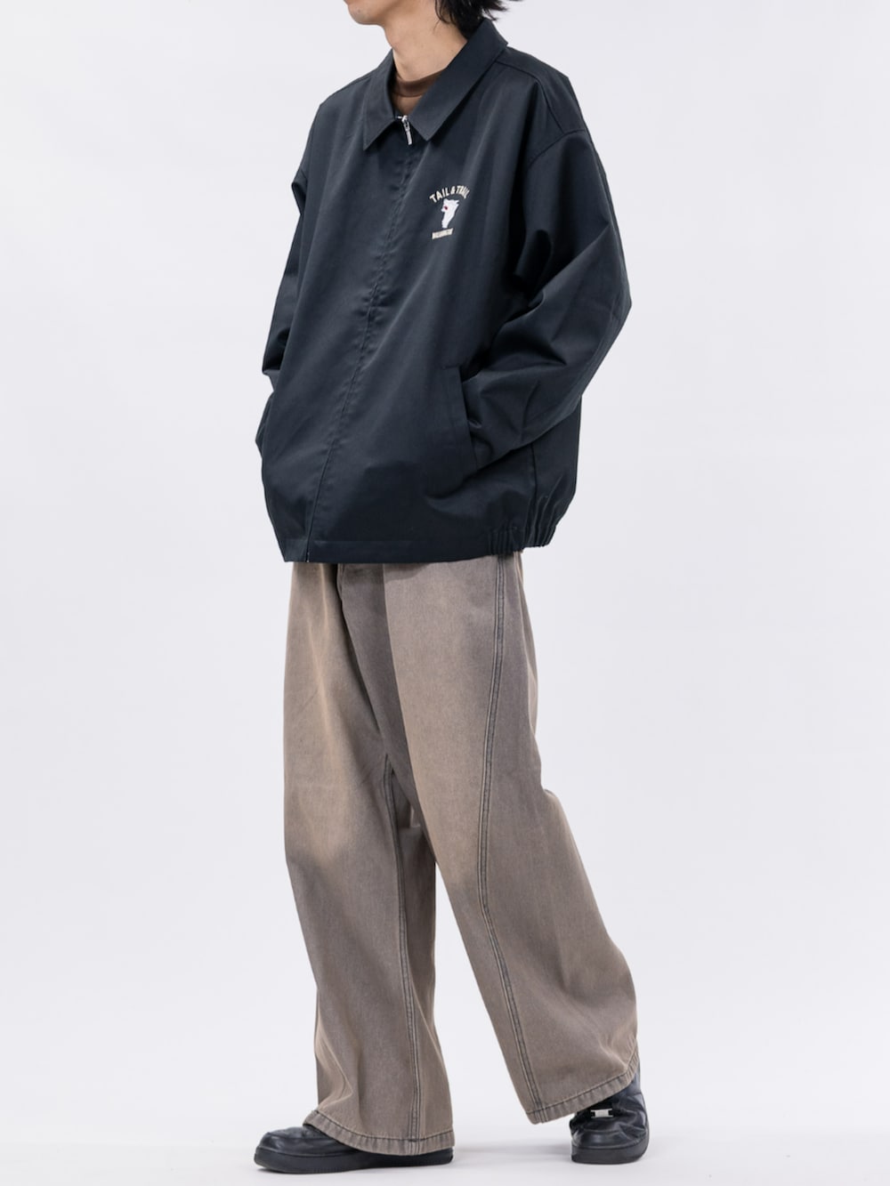 ブラック系のスニーカー、ブラック系のブルゾン、ブラウン系のデニムパンツを着用したメンズの秋コーディネートの2枚目の写真