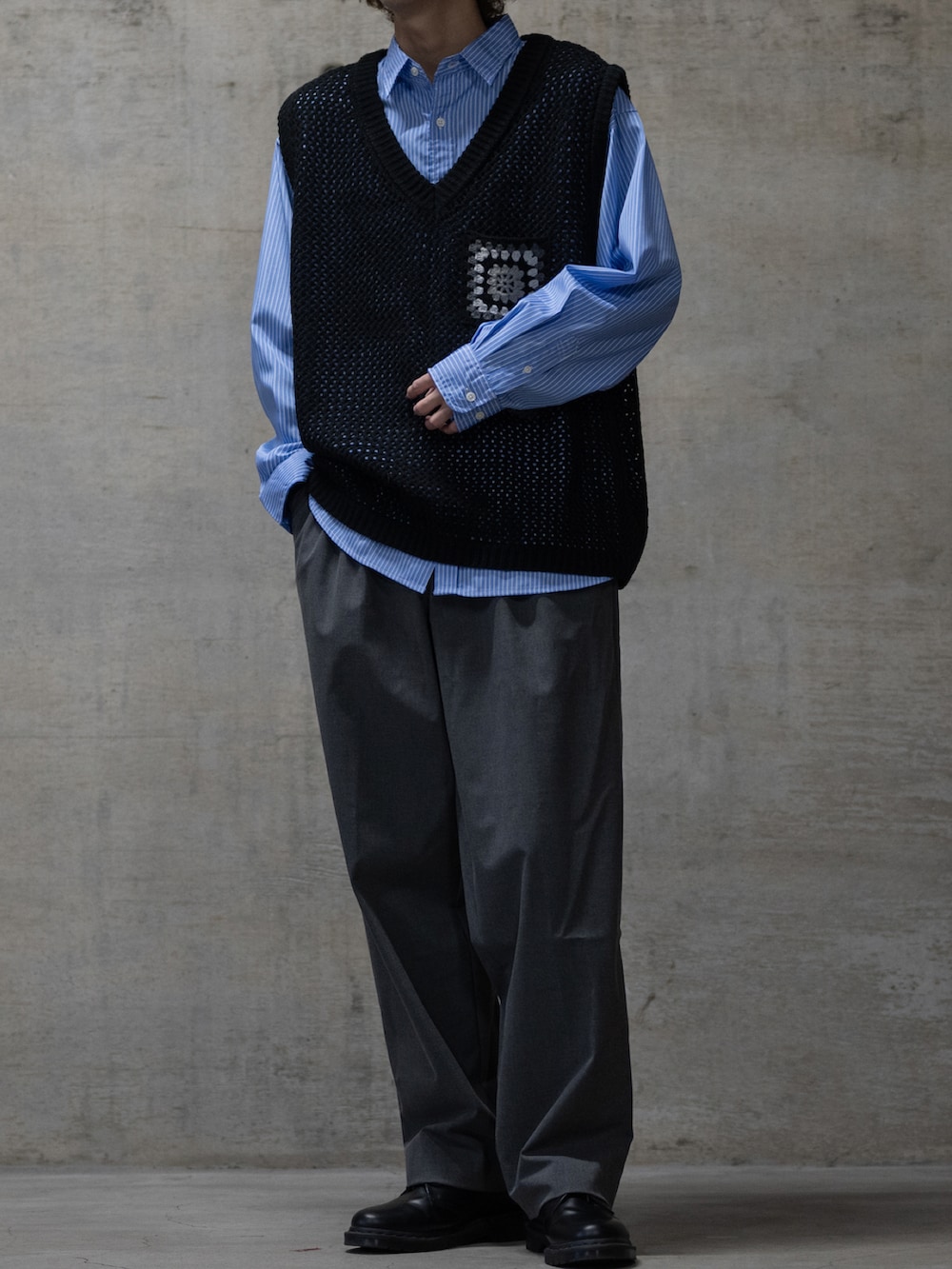 グレー系のスラックス、ブラック系のドレスシューズ、ブラック系のベストを着用したメンズの冬コーディネートの2枚目の写真