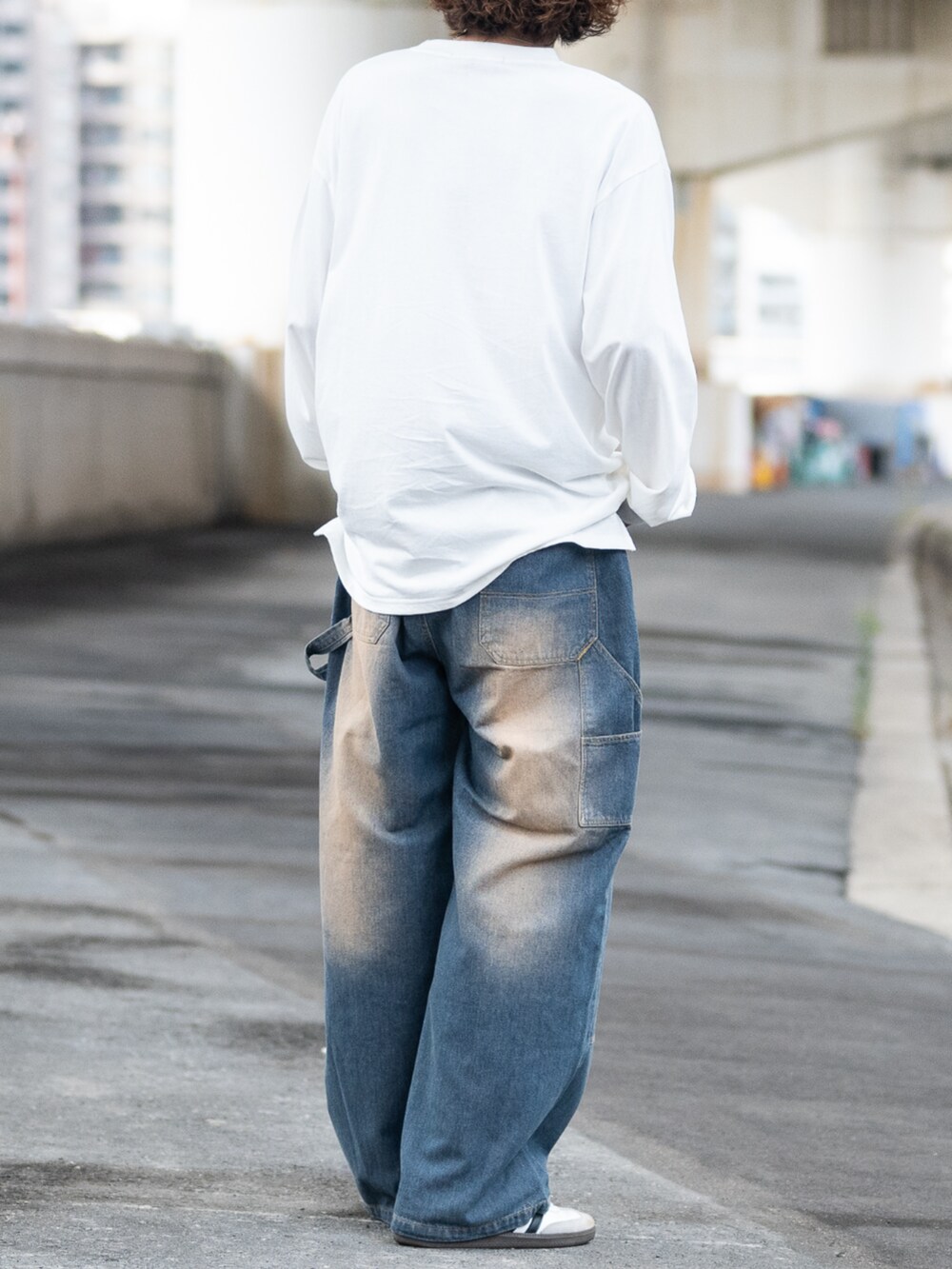 ホワイト系のスニーカー、ホワイト系のTシャツ/カットソー、ブルー系のデニムパンツを着用したメンズの秋コーディネートの3枚目の写真