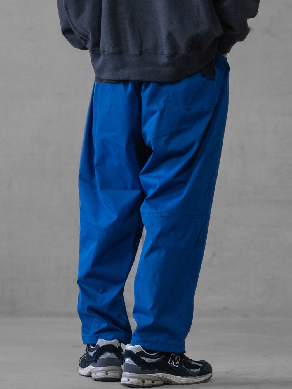 ブラック系のスニーカー、ブルー系のスラックス、ホワイト系のスウェットを着用したメンズの春コーディネートの4枚目の写真