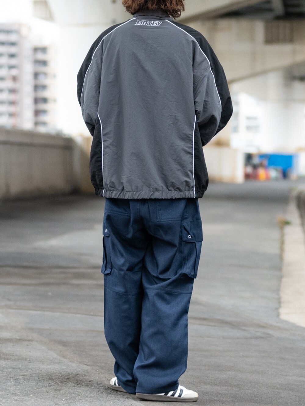 ホワイト系のスニーカー、ブラック系のカーゴパンツ、グレー系のナイロンジャケットを着用したメンズの冬コーディネートの2枚目の写真