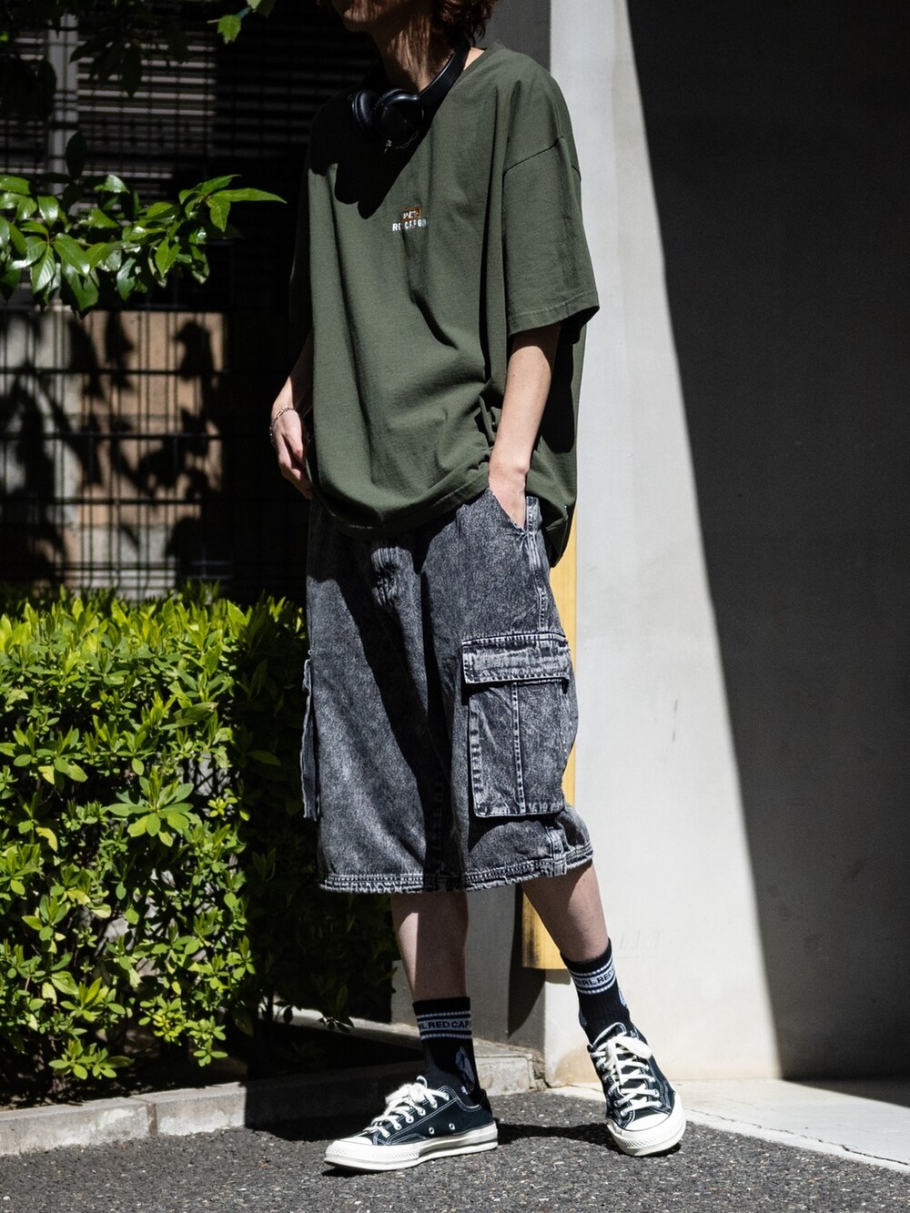 ブラック系のカーゴパンツ、グリーン系のTシャツ/カットソー、ブラック系のスニーカーを着用したメンズの春コーディネートの2枚目の写真