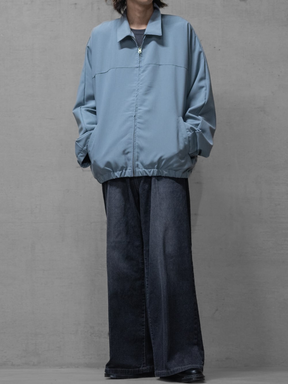 ブラック系のドレスシューズ、ブルー系のデニムパンツ、グレー系のブルゾンを着用したメンズの春コーディネートの2枚目の写真