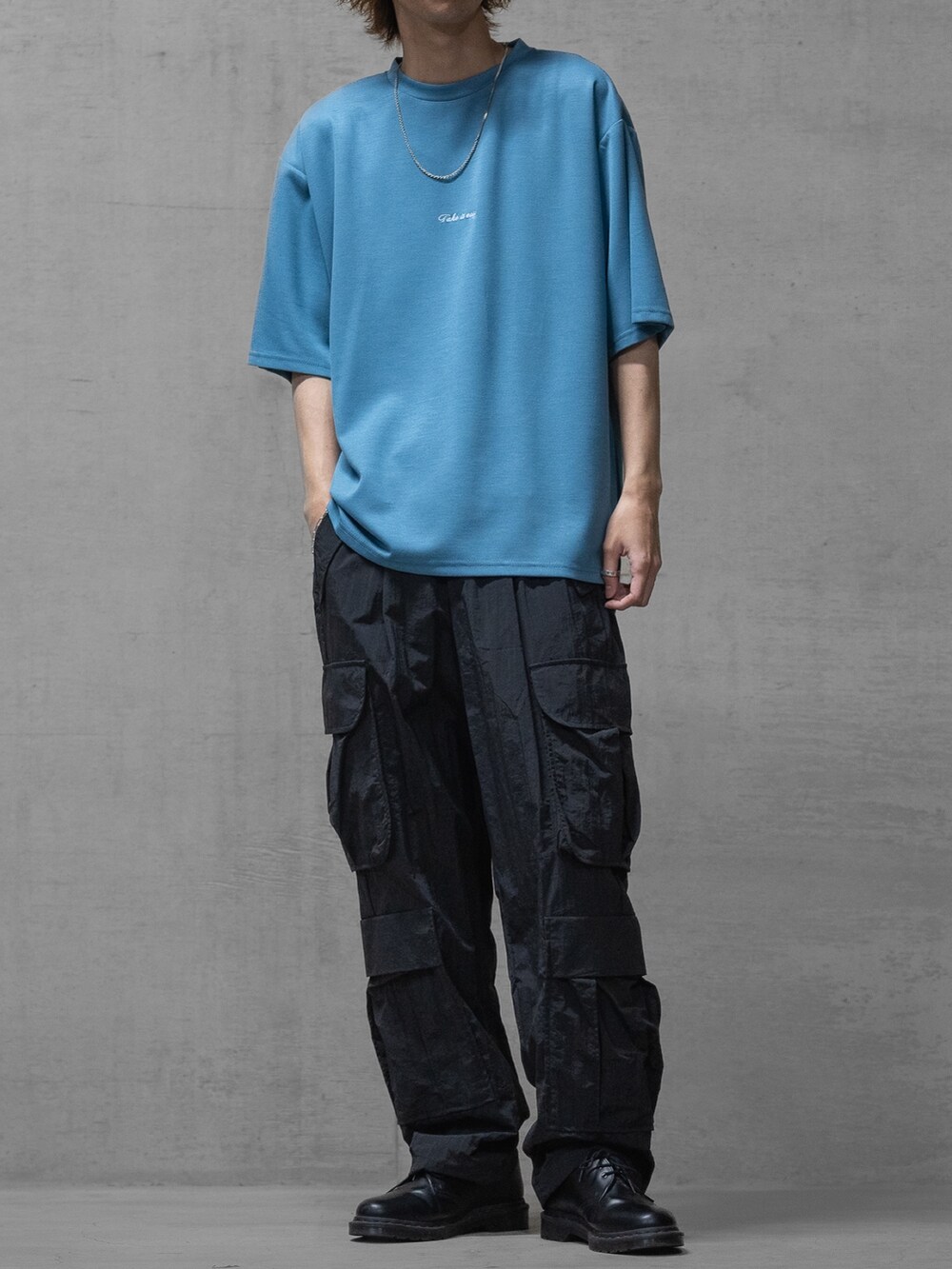 ブラック系のカーゴパンツ、ブラック系のドレスシューズ、ブルー系のTシャツ/カットソーを着用したメンズの春コーディネートの2枚目の写真