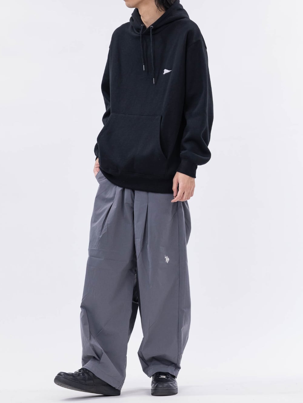 ブラック系のパーカー、グレー系のチノパンツを着用したメンズの冬コーディネートの2枚目の写真