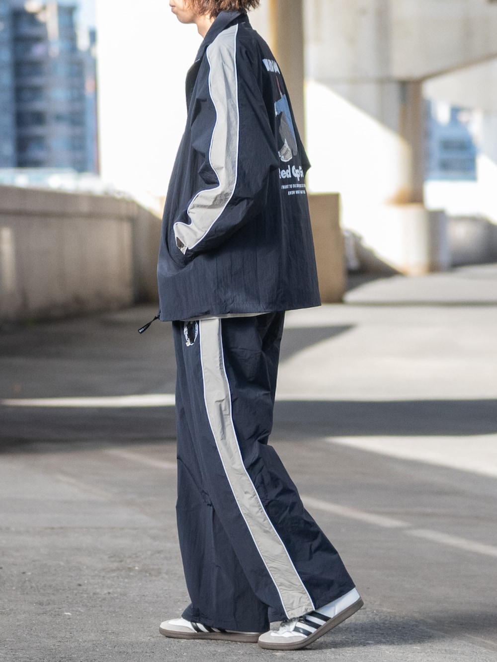 ホワイト系のスニーカー、ブルー系のナイロンジャケット、グレー系のTシャツ/カットソーを着用したメンズの冬コーディネートの2枚目の写真