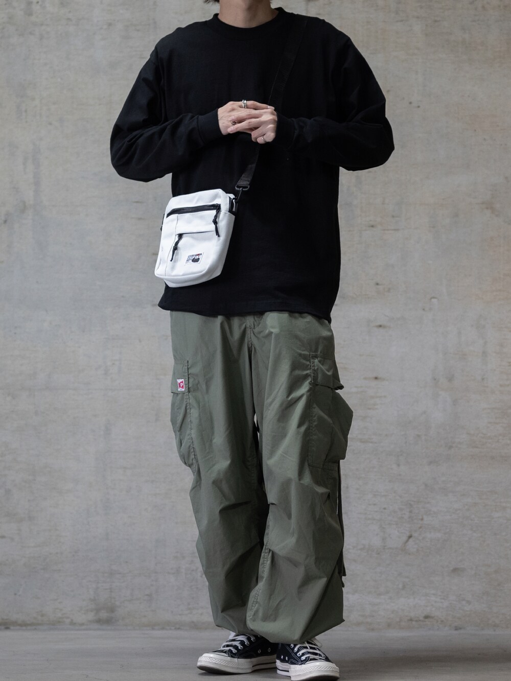 グリーン系のカーゴパンツ、ブラック系のスニーカー、ホワイト系のショルダーバッグを着用したメンズの秋コーディネートの2枚目の写真
