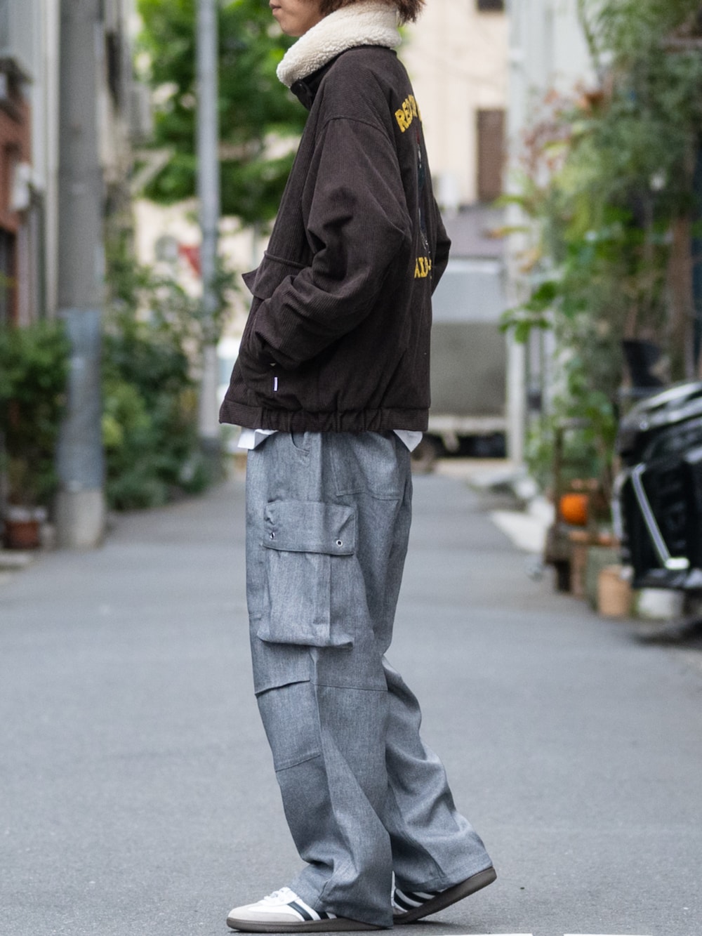 ホワイト系のスニーカー、ブラック系のカーゴパンツ、ブラウン系のミリタリージャケットを着用したメンズの冬コーディネートの2枚目の写真