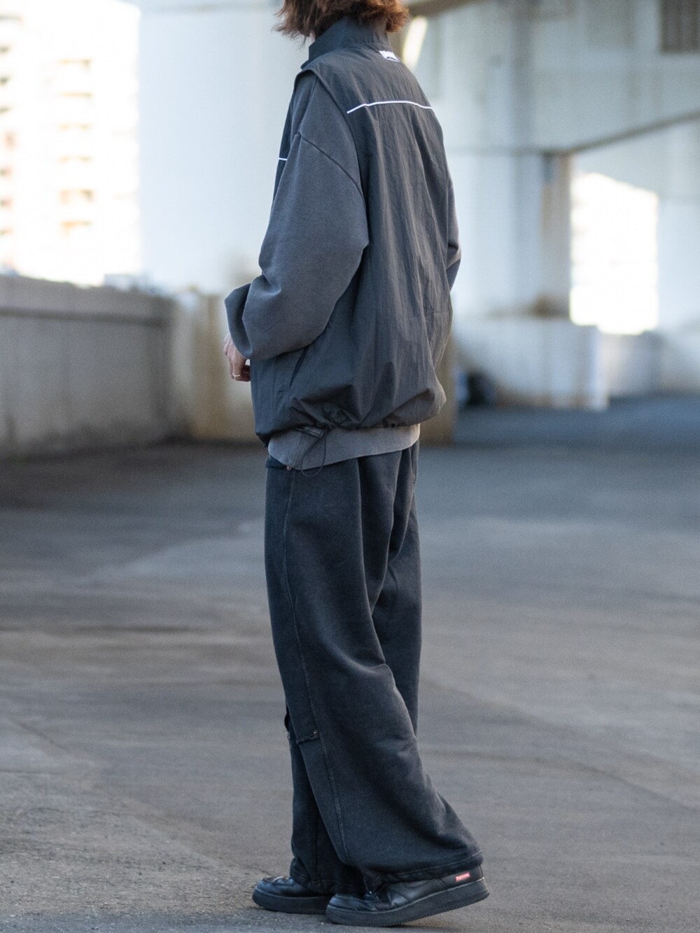 ブラック系のスウェット、グレー系のベスト、ブラック系のスニーカーを着用したメンズの冬コーディネートの2枚目の写真