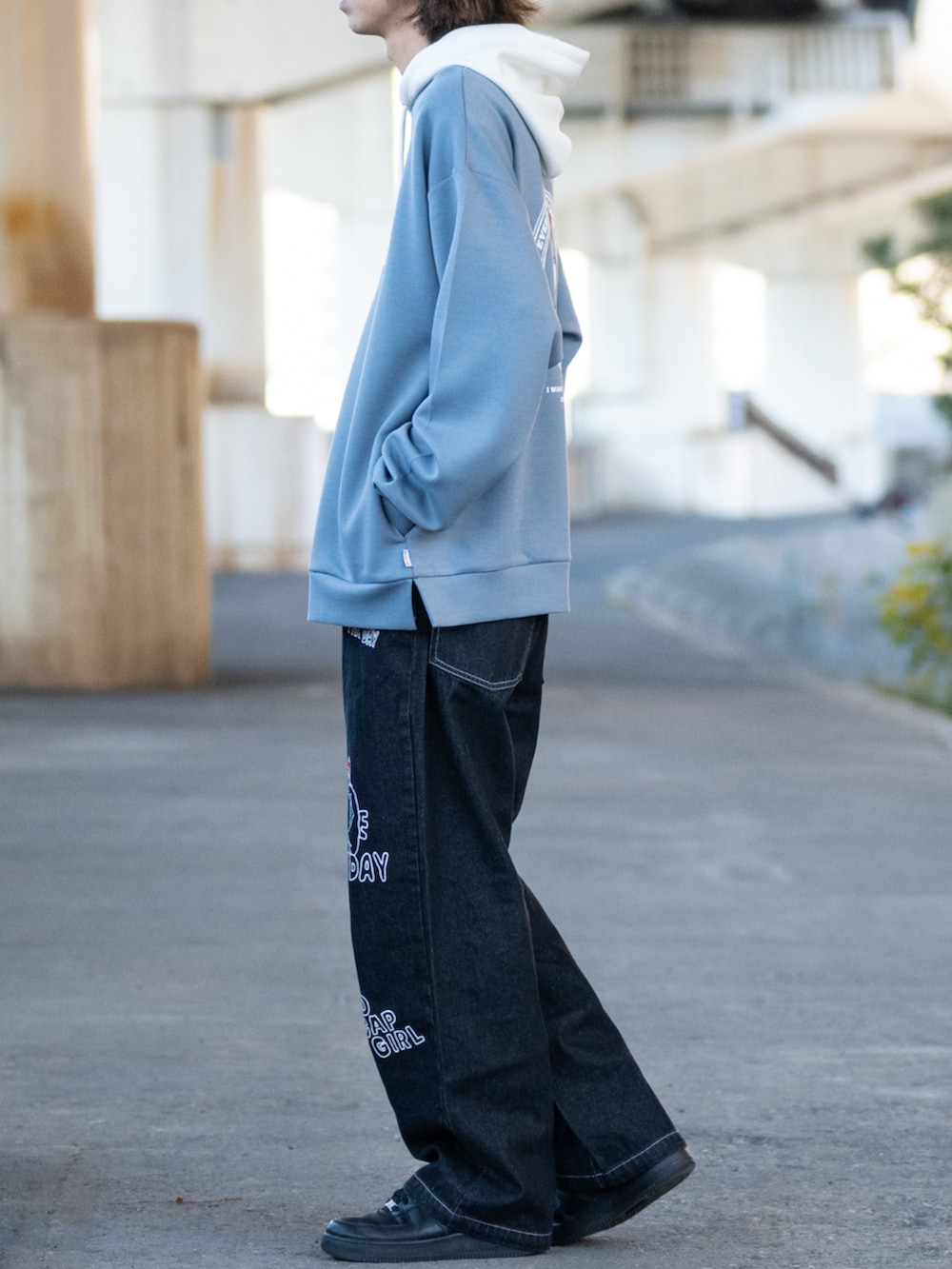 ブラック系のスニーカー、ブラック系のデニムパンツ、ブルー系のパーカーを着用したメンズの冬コーディネートの2枚目の写真