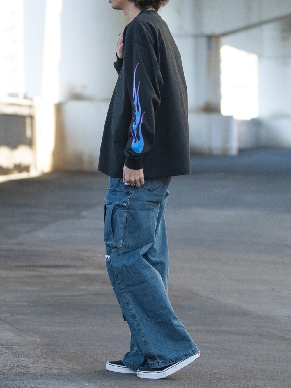 ブルー系のデニムパンツ、ブラック系のスニーカー、ブラック系のTシャツ/カットソーを着用したメンズの冬コーディネートの2枚目の写真