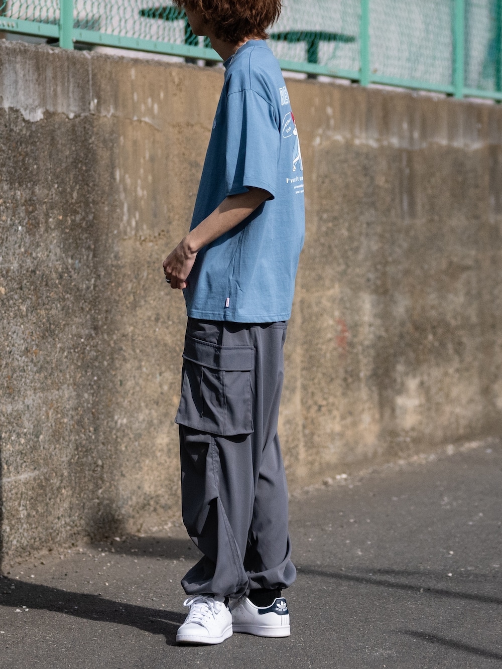 グレー系のカーゴパンツ、ホワイト系のスニーカー、ブルー系のTシャツ/カットソーを着用したメンズの夏コーディネートの2枚目の写真