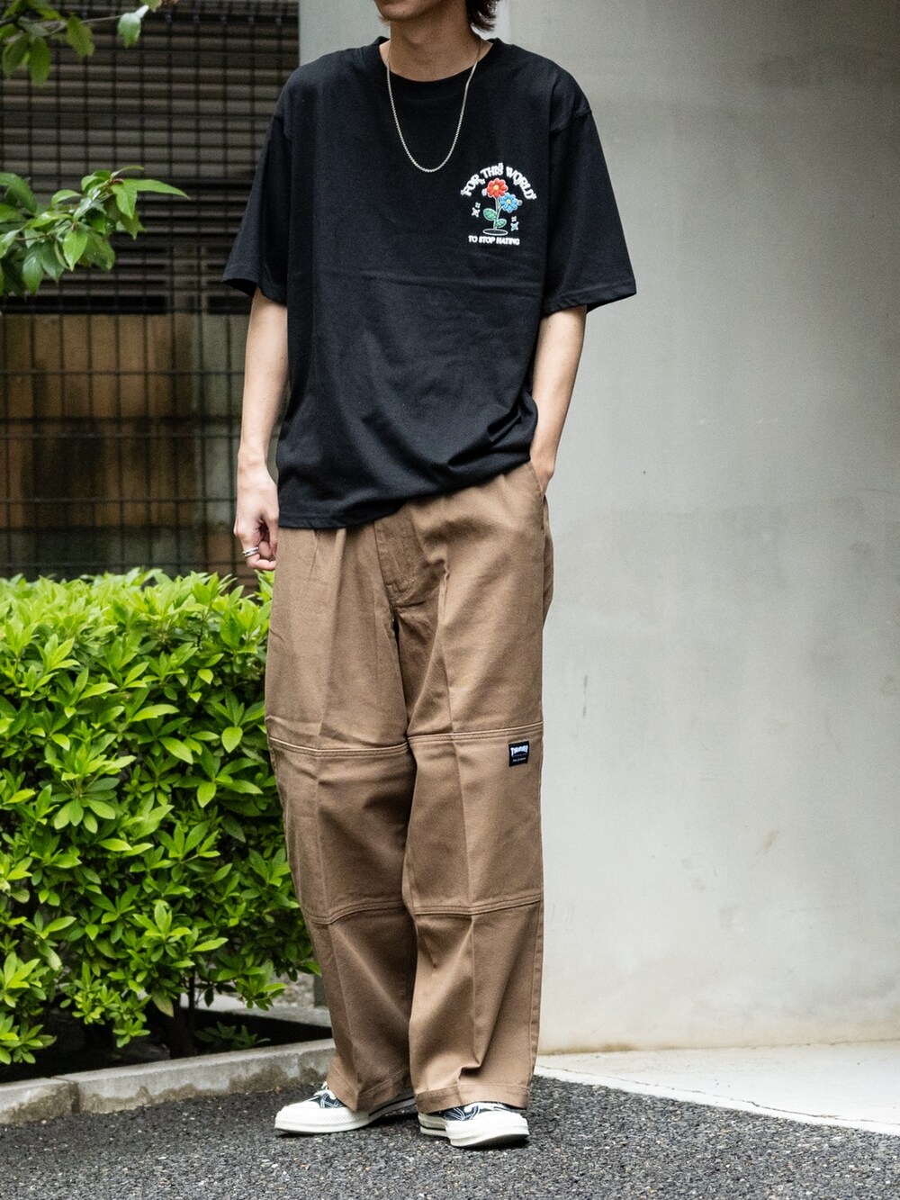 ブラウン系のデニムパンツ、ブラック系のスニーカー、ブラック系のTシャツ/カットソーを着用したメンズの春コーディネートの2枚目の写真