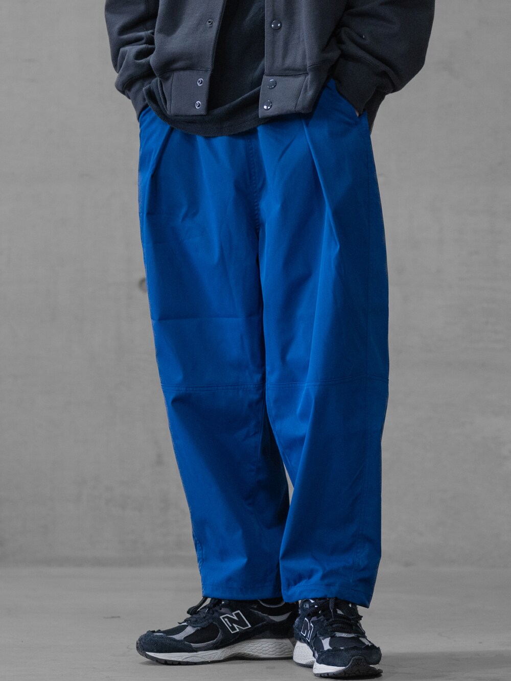 ブラック系のスニーカー、ブルー系のスラックス、ホワイト系のスウェットを着用したメンズの春コーディネートの2枚目の写真