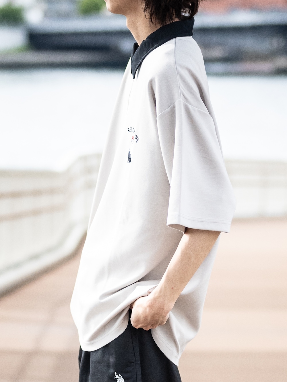 ベージュ系のポロシャツ、ブラック系のチノパンツ、ブラック系のスニーカーを着用したメンズの夏コーディネートの3枚目の写真