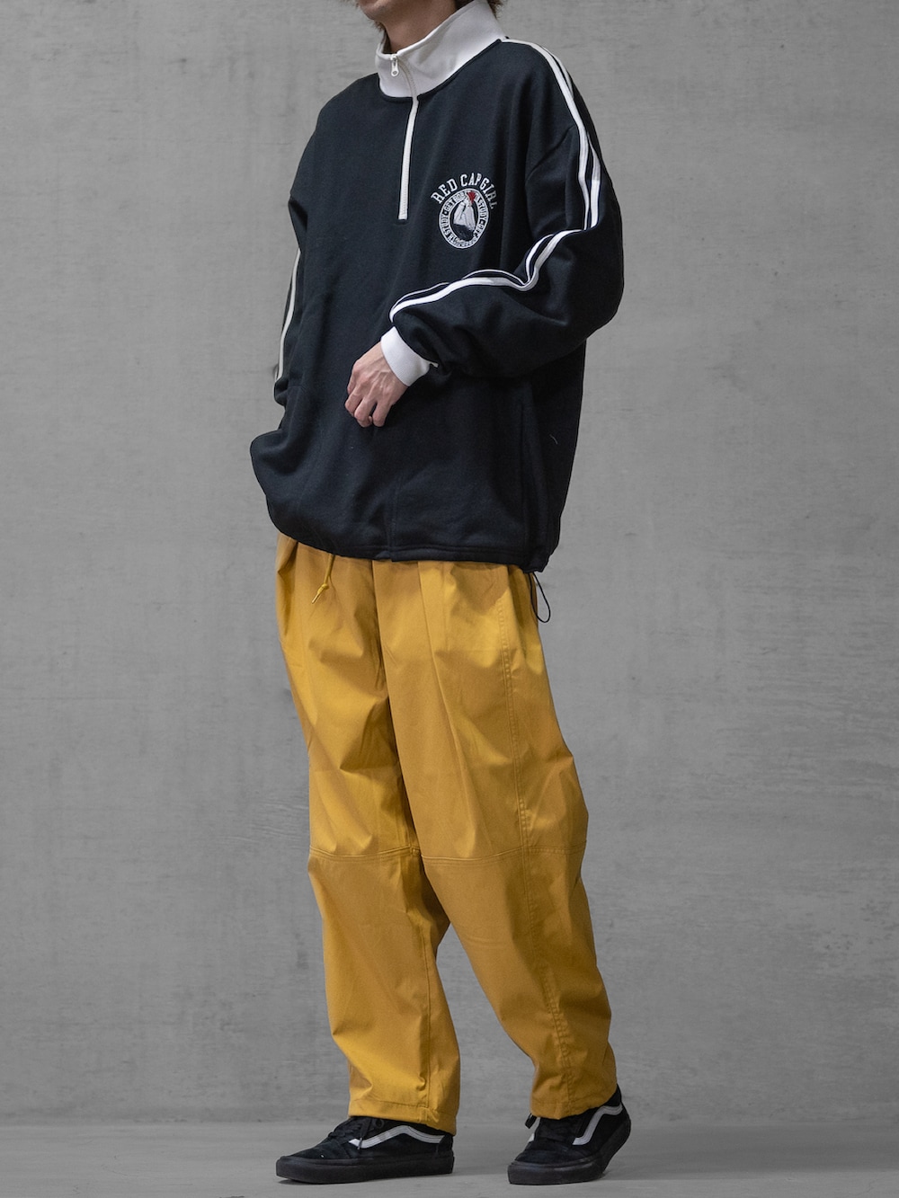 イエロー系のスラックス、ブラック系のスニーカー、ホワイト系のスウェットを着用したメンズの春コーディネートの2枚目の写真