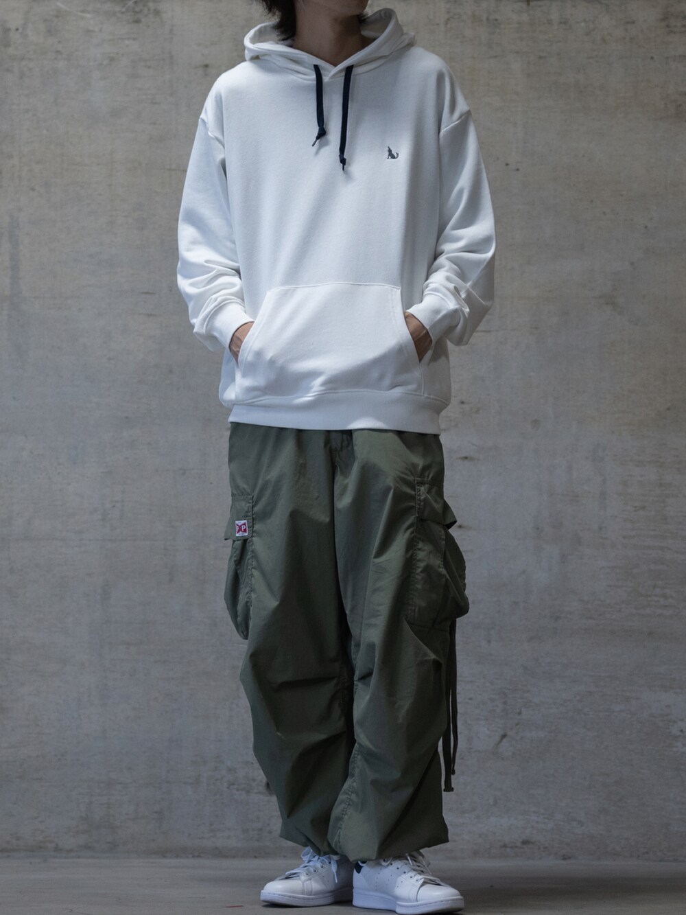 ホワイト系のスニーカー、グリーン系のカーゴパンツ、ホワイト系のパーカーを着用したメンズの秋コーディネートの2枚目の写真