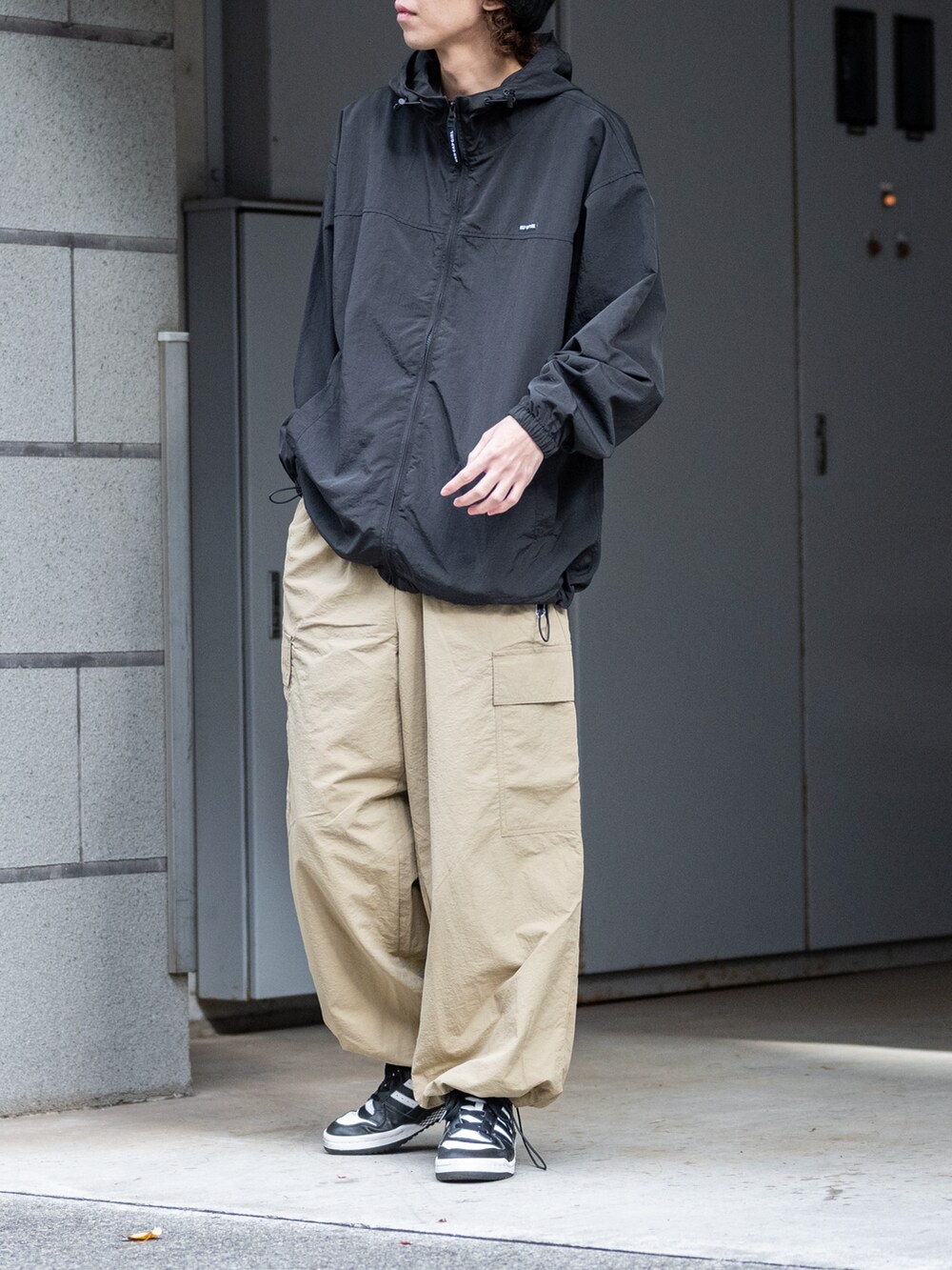 ベージュ系のカーゴパンツ、ブラック系のナイロンジャケットを着用したメンズの春コーディネートの2枚目の写真