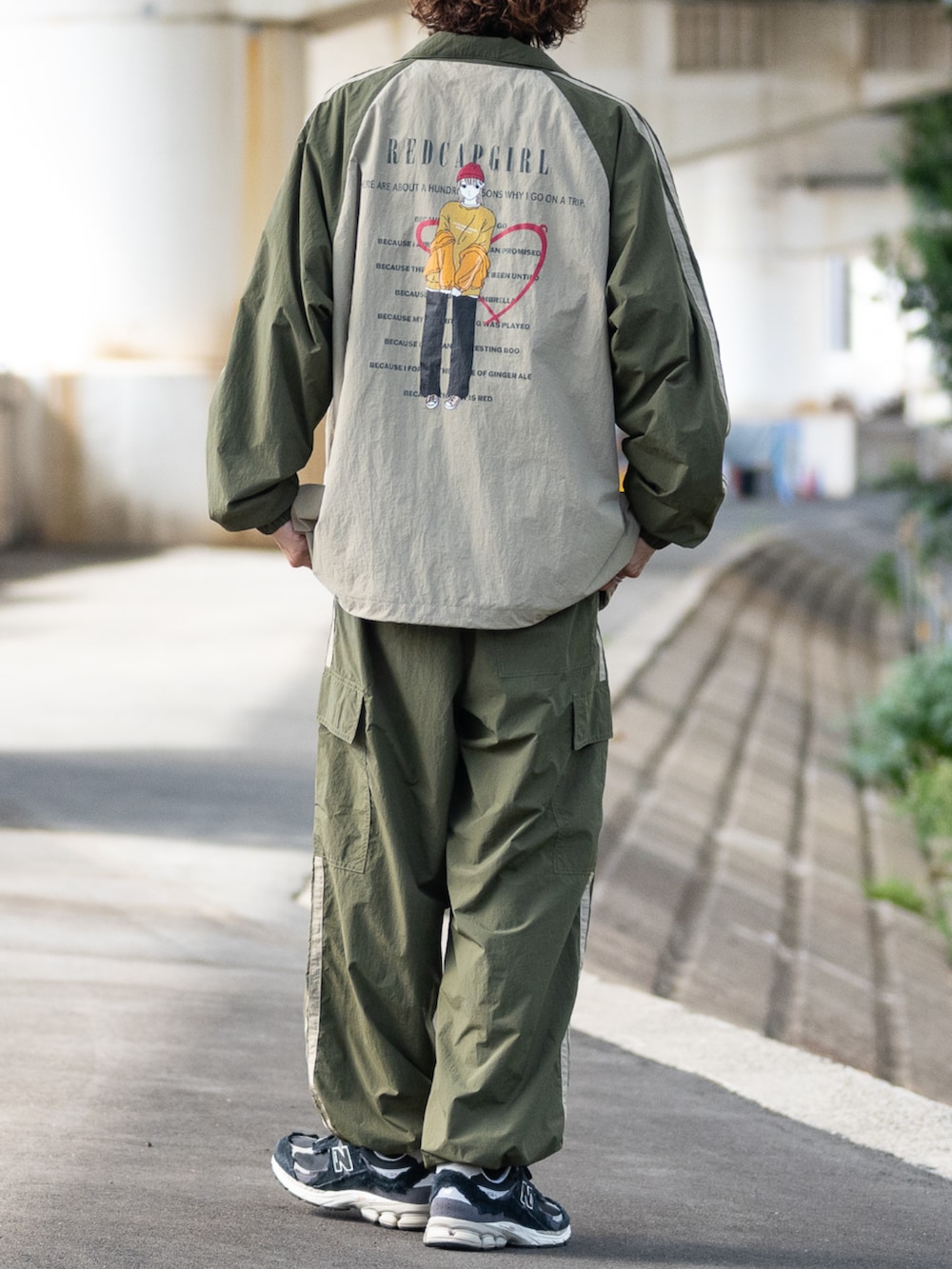 ブラック系のスニーカー、グリーン系のナイロンジャケット、グリーン系のカーゴパンツを着用したメンズの秋コーディネートの3枚目の写真