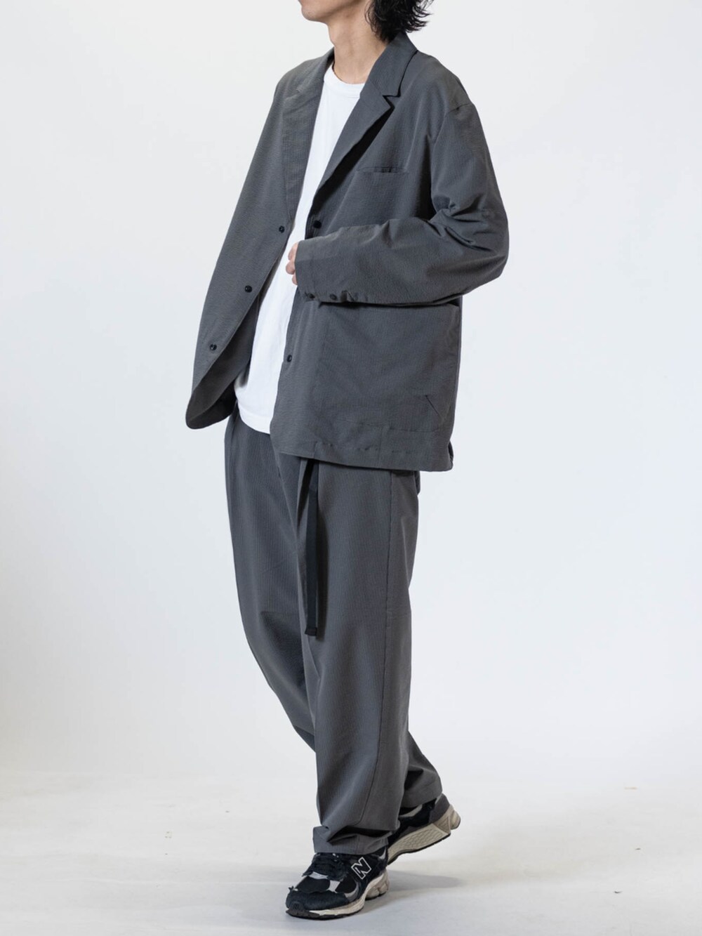 ホワイト系のTシャツ/カットソー、ブラック系のスニーカー、グレー系のチノパンツを着用したメンズの夏コーディネートの2枚目の写真