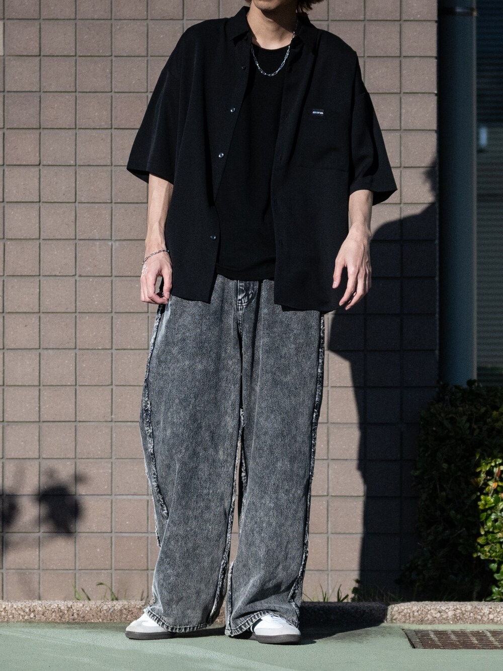 ブラック系のデニムパンツ、ホワイト系のスニーカー、ブラック系のシャツ/ブラウスを着用したメンズの春コーディネートの2枚目の写真