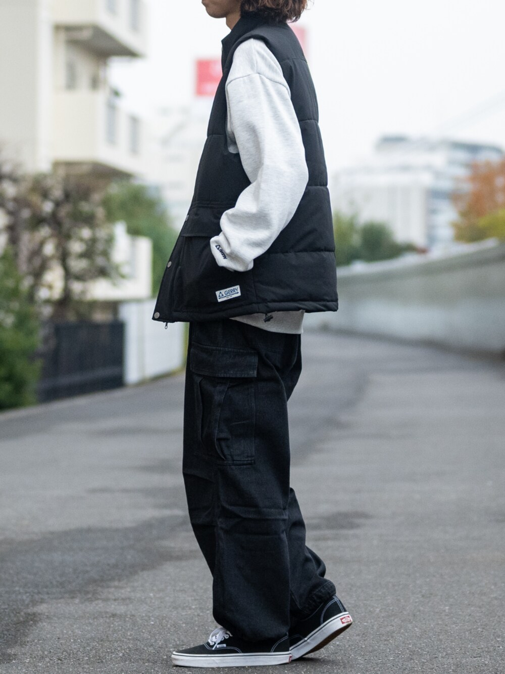 ブラック系のデニムパンツ、ベージュ系のスウェット、ブラック系のダウンベストを着用したメンズの冬コーディネートの2枚目の写真