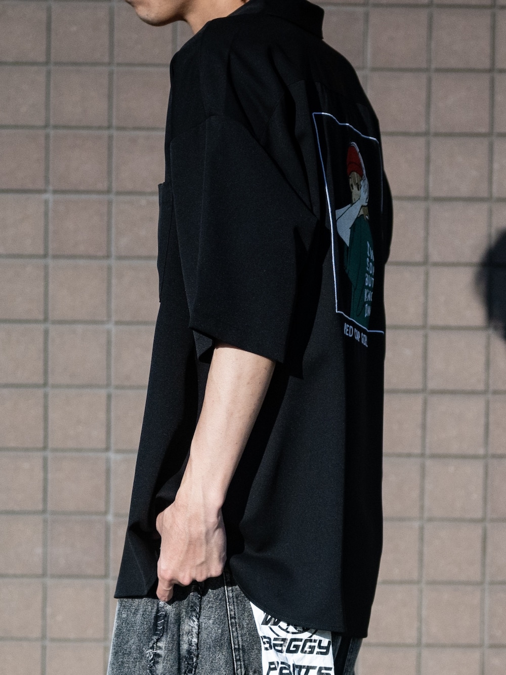 ブラック系のデニムパンツ、ホワイト系のスニーカー、ブラック系のシャツ/ブラウスを着用したメンズの春コーディネートの4枚目の写真