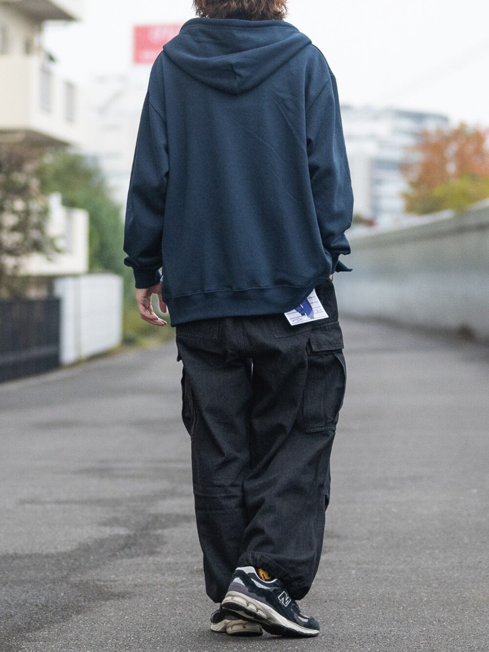 ブラック系のスニーカー、ブラック系のデニムパンツ、ブルー系のパーカーを着用したメンズの冬コーディネートの3枚目の写真