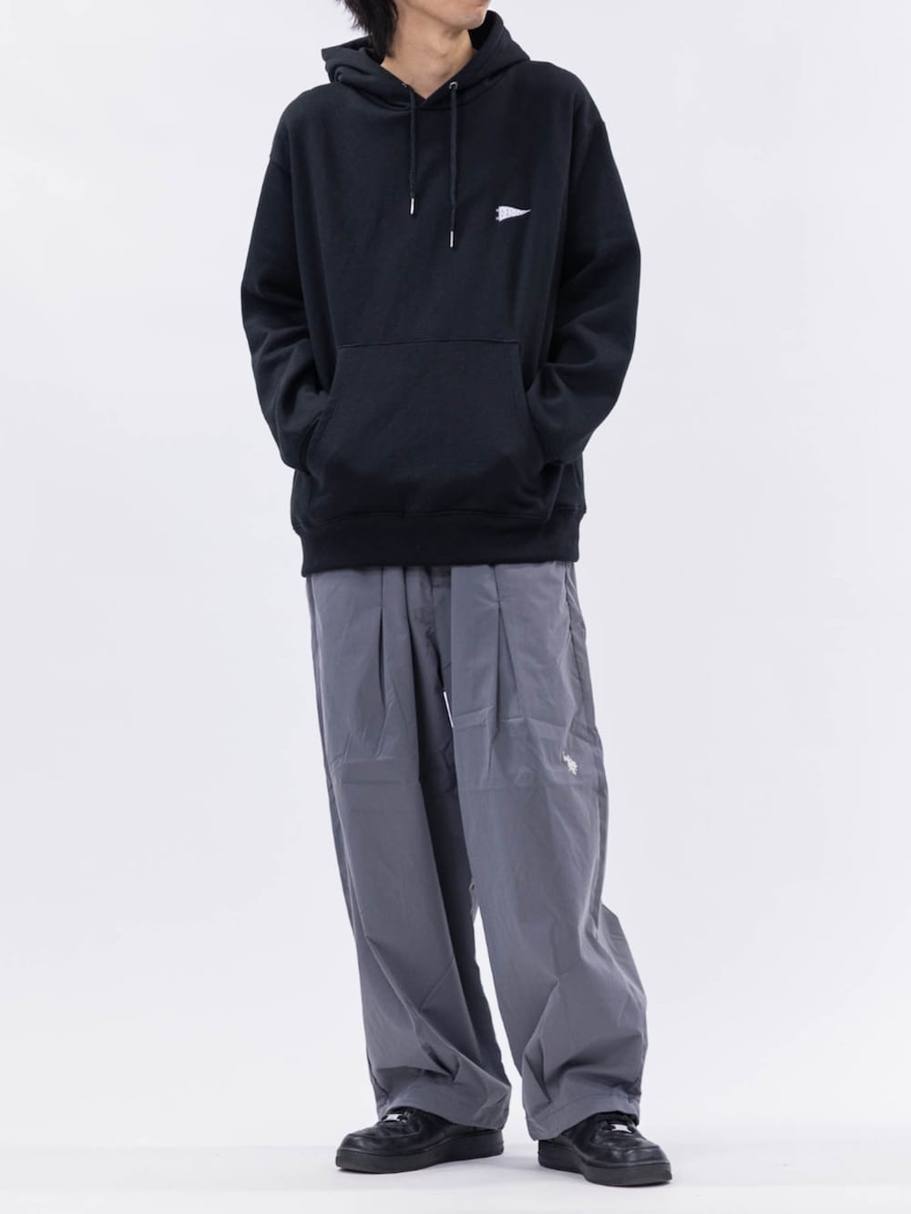 ブラック系のパーカー、グレー系のチノパンツを着用したメンズの冬コーディネートの3枚目の写真