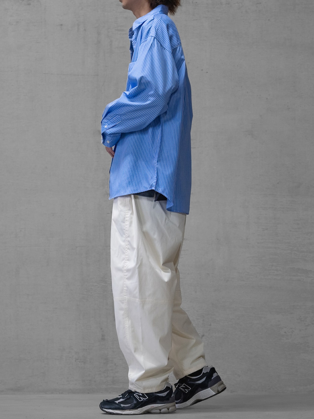 ブラック系のスニーカー、ホワイト系のスラックス、ブルー系のシャツ/ブラウスを着用したメンズの春コーディネートの2枚目の写真