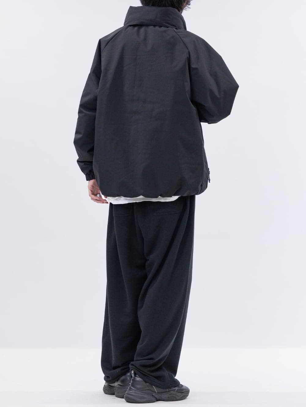 ブラック系のスウェットパンツ、ブラック系のミリタリージャケット、ホワイト系のTシャツ/カットソーを着用したメンズの冬コーディネートの3枚目の写真