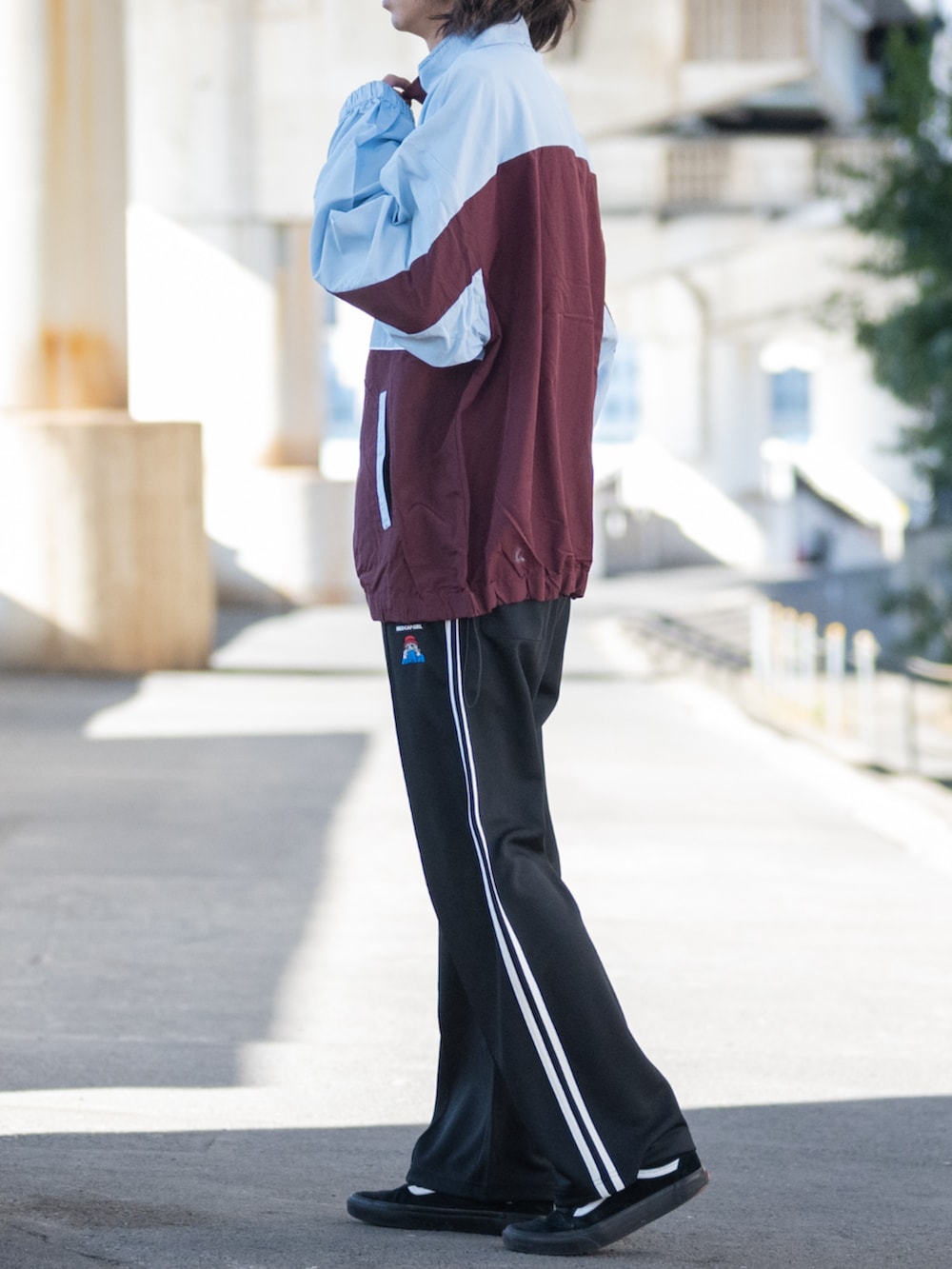 ブラック系のスニーカー、レッド系のナイロンジャケット、ブラック系のその他パンツを着用したメンズの春コーディネートの2枚目の写真