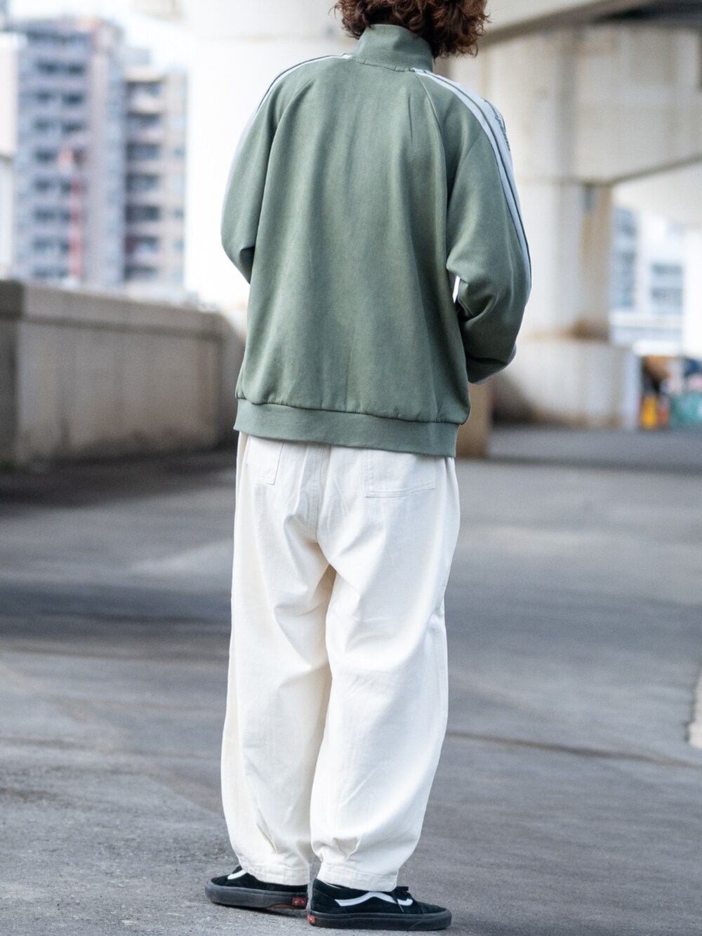 ホワイト系のデニムパンツ、グリーン系のジャージを着用したメンズの秋コーディネートの3枚目の写真