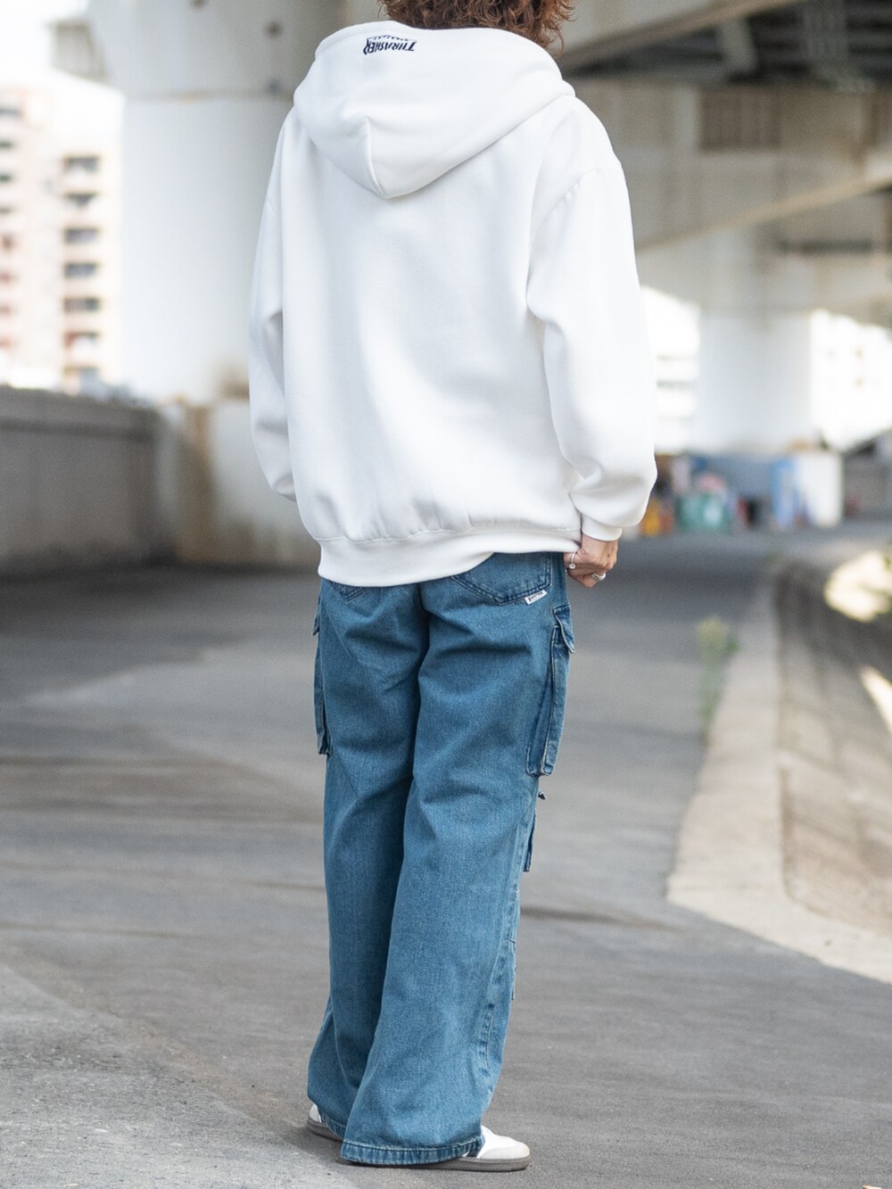 ホワイト系のスニーカー、ブルー系のデニムパンツ、ホワイト系のパーカーを着用したメンズの秋コーディネートの3枚目の写真