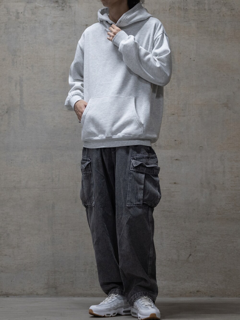 ブラック系のデニムパンツ、ホワイト系のスニーカー、グレー系のパーカーを着用したメンズの秋コーディネートの2枚目の写真
