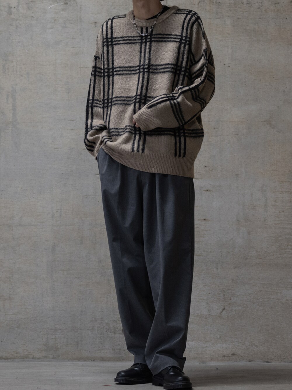 グレー系のスラックス、ブラック系のブーツ、ベージュ系のニット/セーターを着用したメンズの冬コーディネートの2枚目の写真