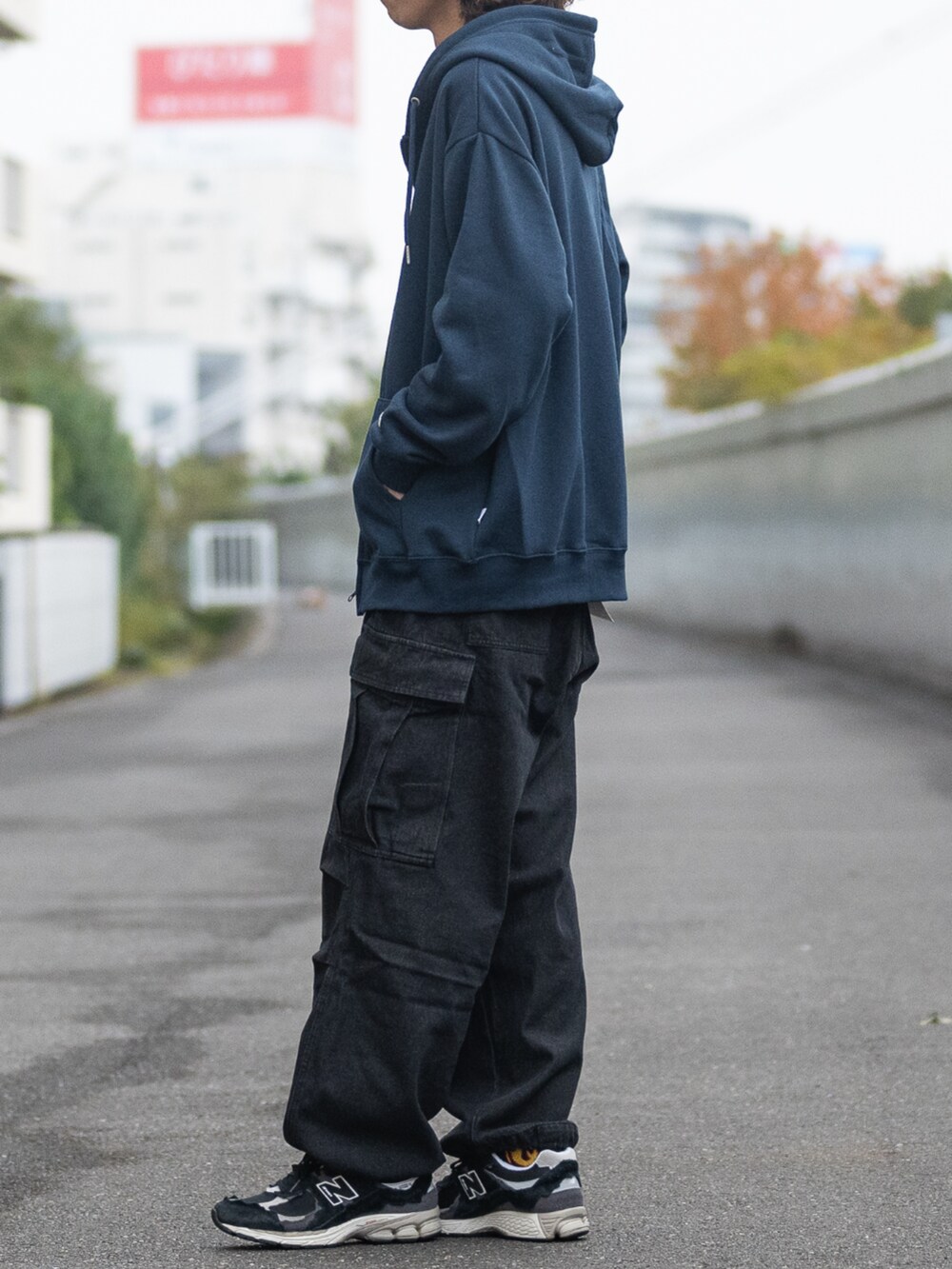 ブラック系のスニーカー、ブラック系のデニムパンツ、ブルー系のパーカーを着用したメンズの冬コーディネートの2枚目の写真