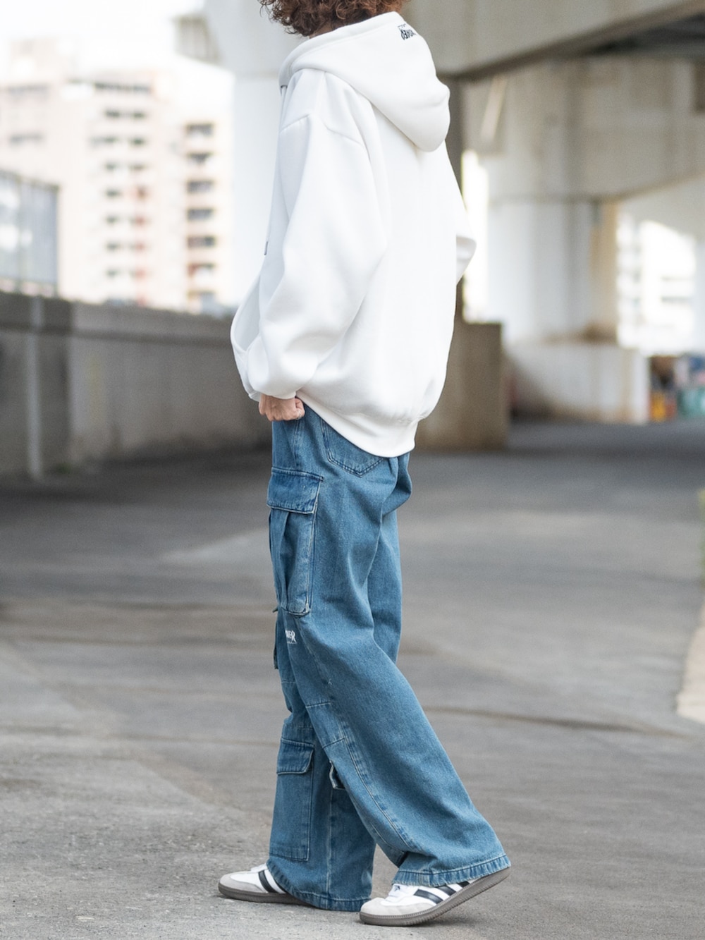 ホワイト系のスニーカー、ブルー系のデニムパンツ、ホワイト系のパーカーを着用したメンズの秋コーディネートの2枚目の写真