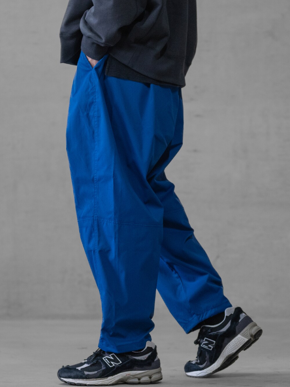 ブラック系のスニーカー、ブルー系のスラックス、ホワイト系のスウェットを着用したメンズの春コーディネートの3枚目の写真