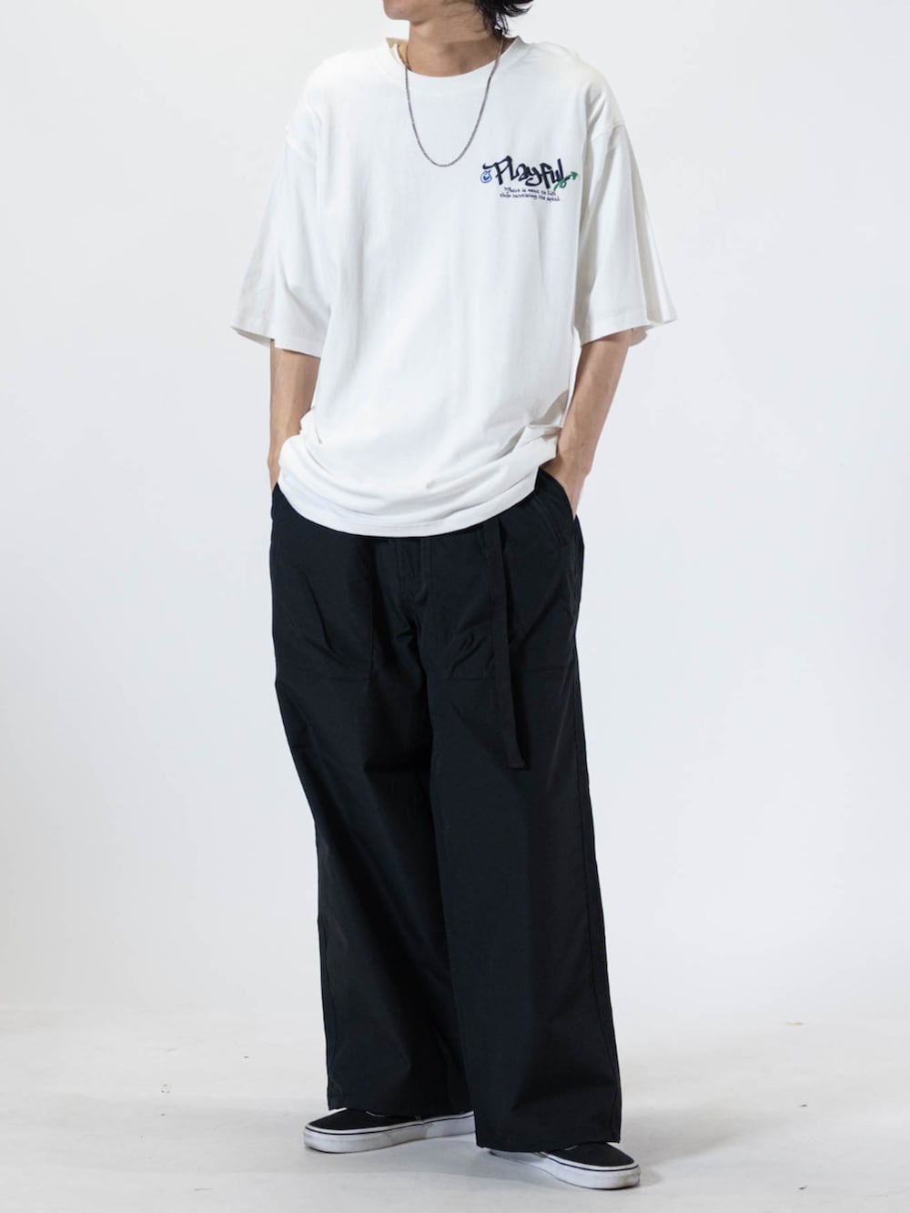 ブラック系のスニーカー、グリーン系のチノパンツ、ホワイト系のTシャツ/カットソーを着用したメンズの夏コーディネートの3枚目の写真