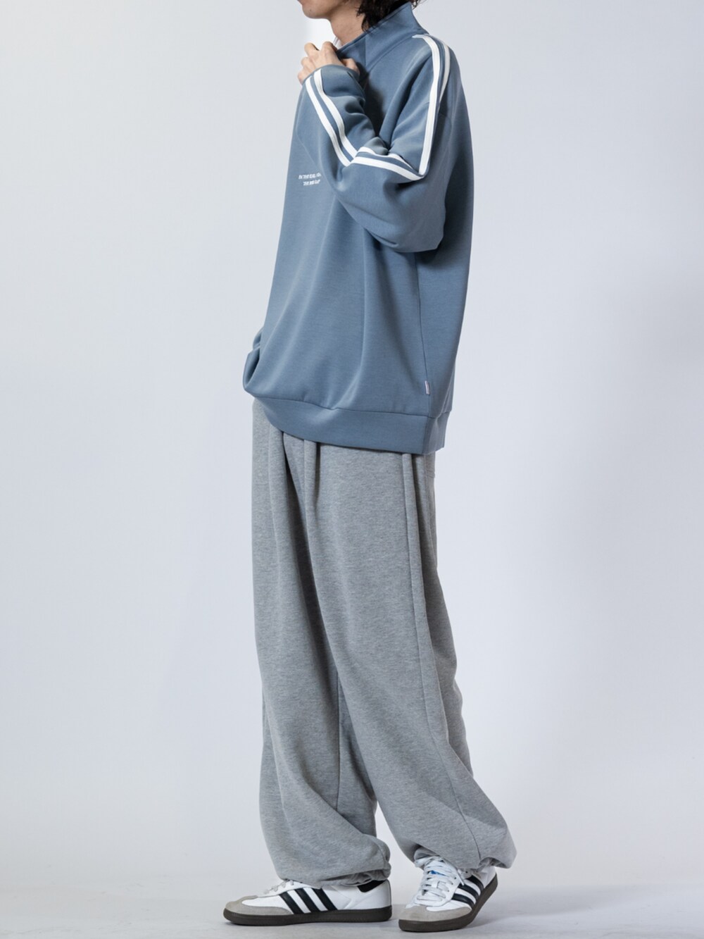 ホワイト系のスニーカー、グレー系のスウェットパンツ、ブルー系のスウェットを着用したメンズの春コーディネートの2枚目の写真