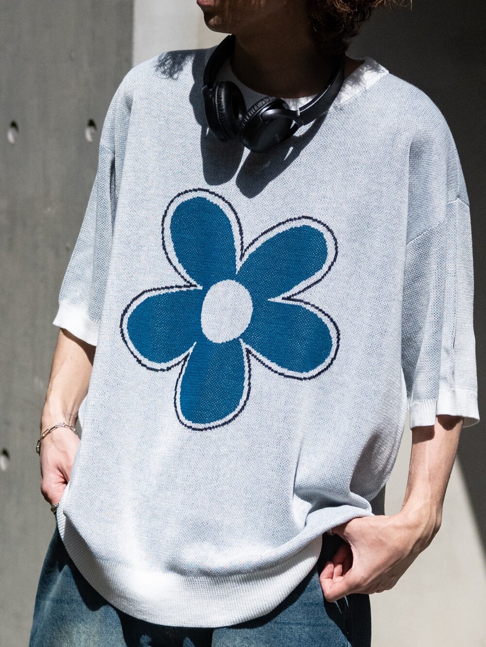 ブルー系のデニムパンツ、ホワイト系のスニーカー、ホワイト系のニット/セーターを着用したメンズの春コーディネートの2枚目の写真