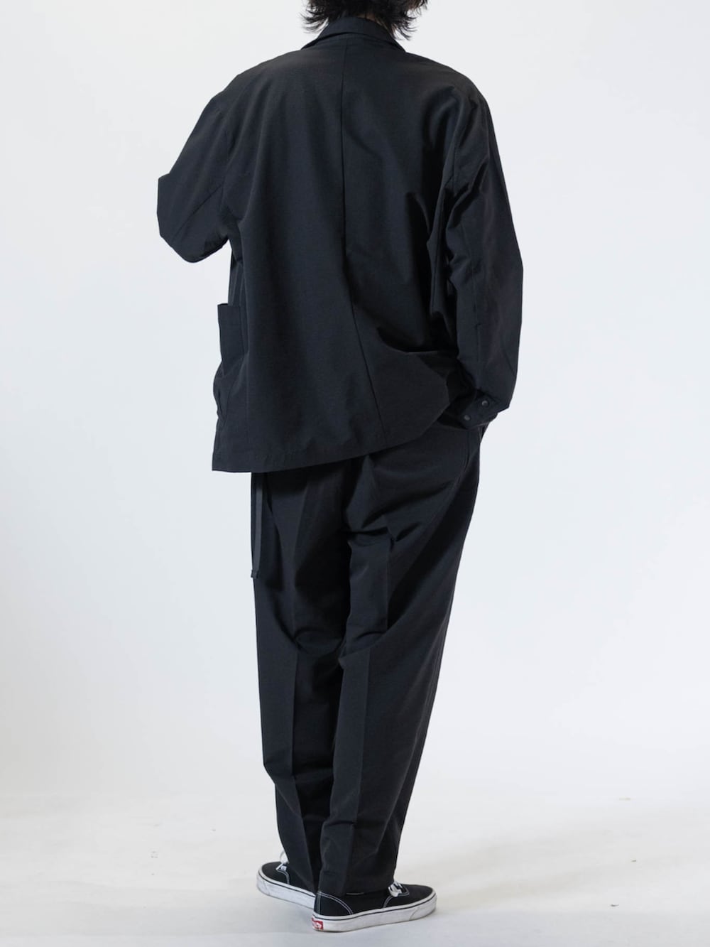 ブラック系のスニーカー、ブラック系のテーラードジャケット、ブラック系のチノパンツを着用したメンズの夏コーディネートの3枚目の写真