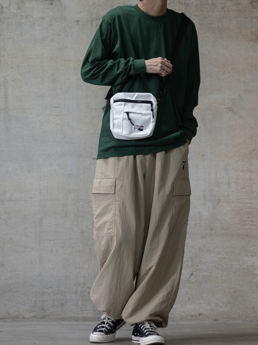 ブラック系のスニーカー、ブラック系のショルダーバッグ、グリーン系のTシャツ/カットソーを着用したメンズの夏コーディネートの2枚目の写真