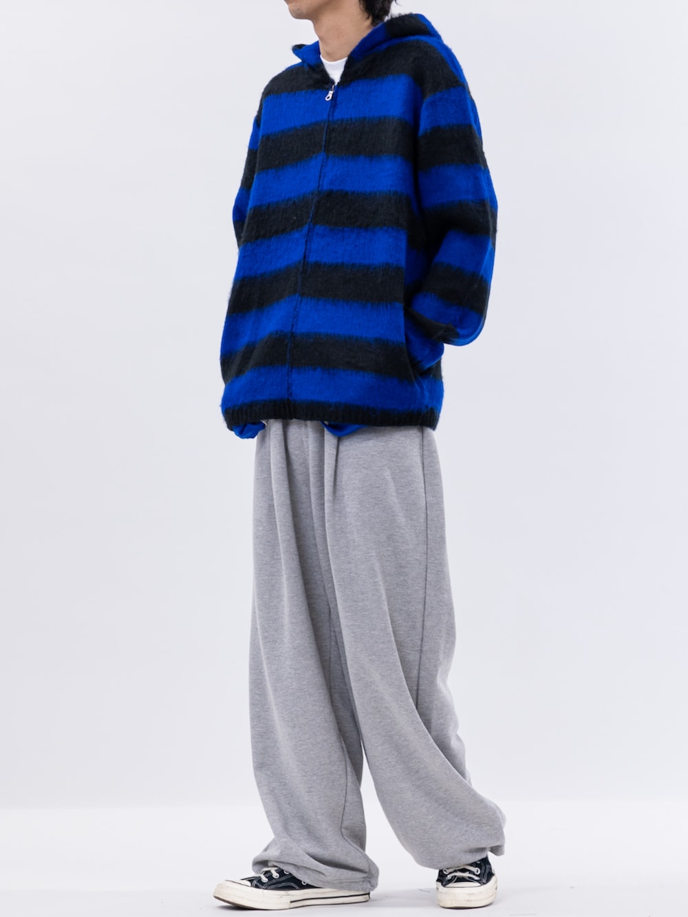 ブラック系のスニーカー、グレー系のスラックス、ブルー系のニット/セーターを着用したメンズの冬コーディネートの2枚目の写真