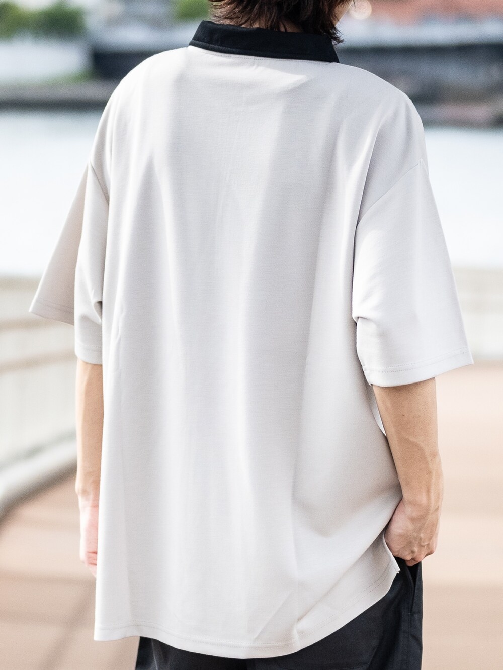 ベージュ系のポロシャツ、ブラック系のチノパンツ、ブラック系のスニーカーを着用したメンズの夏コーディネートの4枚目の写真