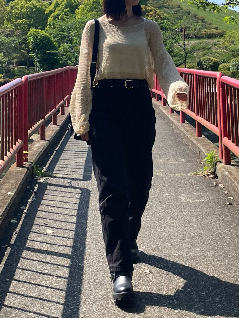 ベージュ系のニット/セーター、ブラック系のショルダーバッグ、ブラック系のデニムパンツを着用したレディースの春コーディネートの2枚目の写真