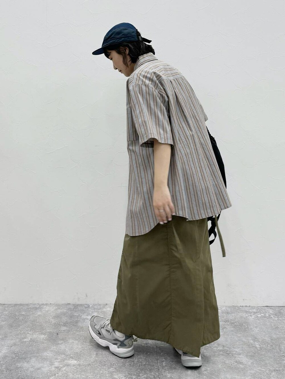 ブラック系のバックパック/リュック、グリーン系のスカート、ホワイト系のTシャツ/カットソーを着用したレディースの春コーディネートの4枚目の写真